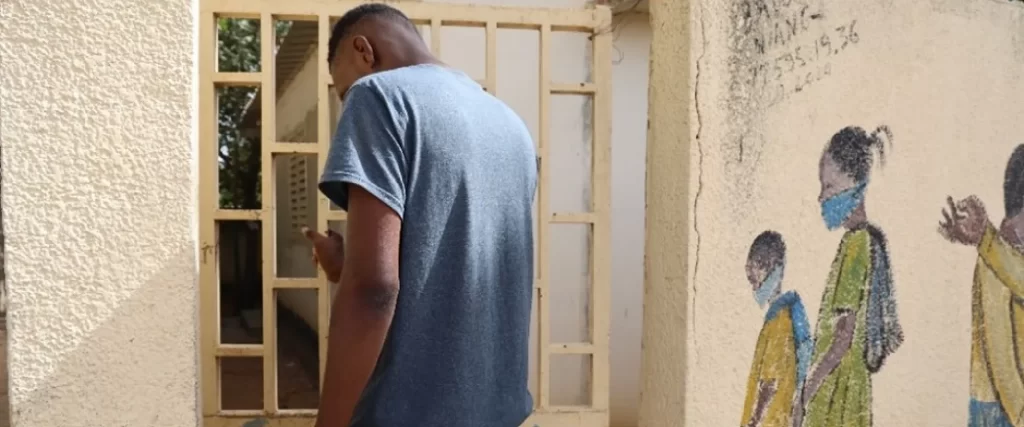 Moussa entrant dans le poste de santé en utilisant la porte d'accès discrète
